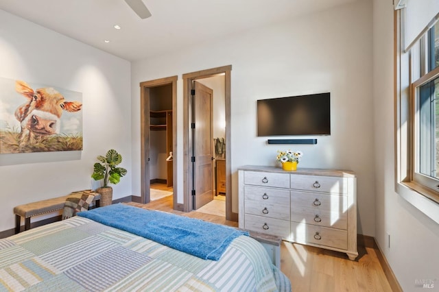 bedroom with connected bathroom, a spacious closet, ceiling fan, light hardwood / wood-style floors, and a closet