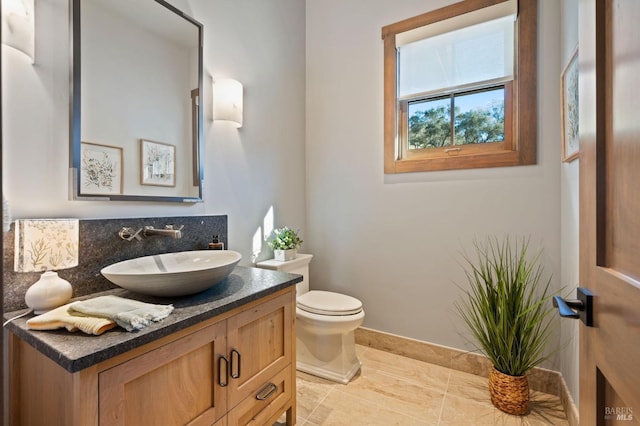 bathroom featuring vanity, toilet, tile patterned floors, and decorative backsplash