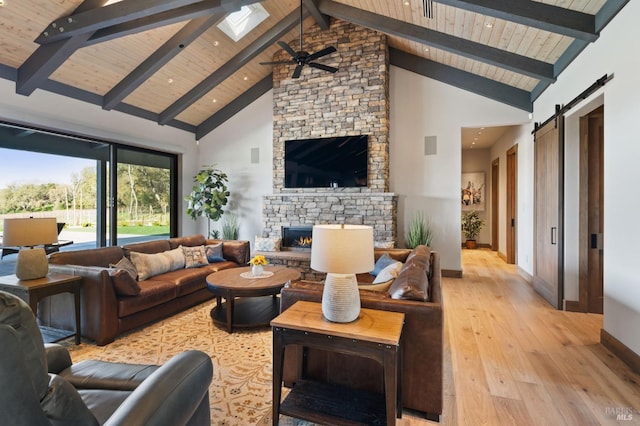 living room with beam ceiling, a barn door, high vaulted ceiling, and a fireplace