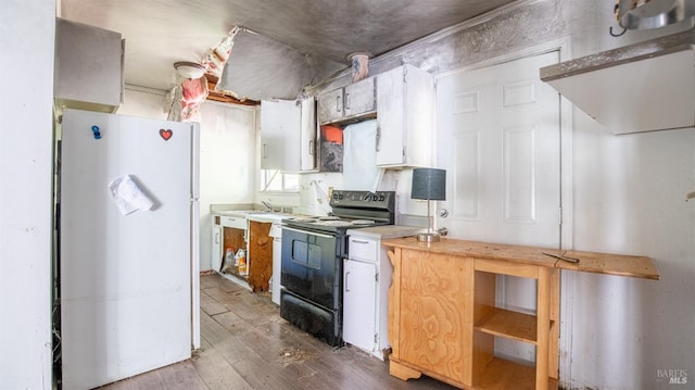 kitchen with black range with electric stovetop, light hardwood / wood-style floors, and white fridge