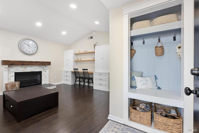 mudroom featuring dark hardwood / wood-style floors, built in desk, vaulted ceiling, and a stone fireplace