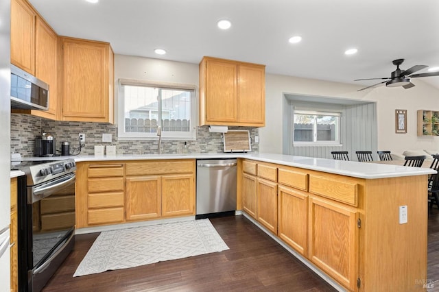 kitchen with sink, backsplash, dark hardwood / wood-style flooring, kitchen peninsula, and stainless steel appliances