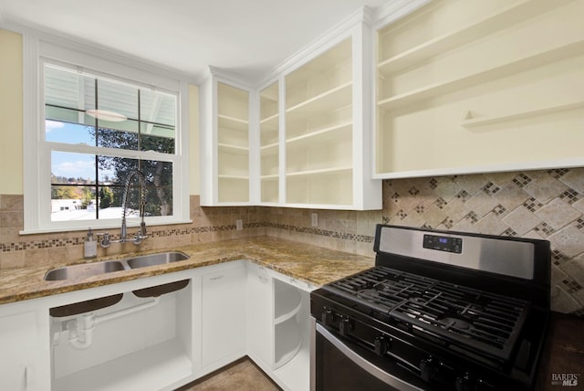 kitchen featuring tasteful backsplash, white cabinetry, sink, light stone countertops, and gas range oven