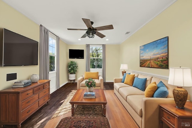 living room with dark wood-type flooring, ornamental molding, and ceiling fan