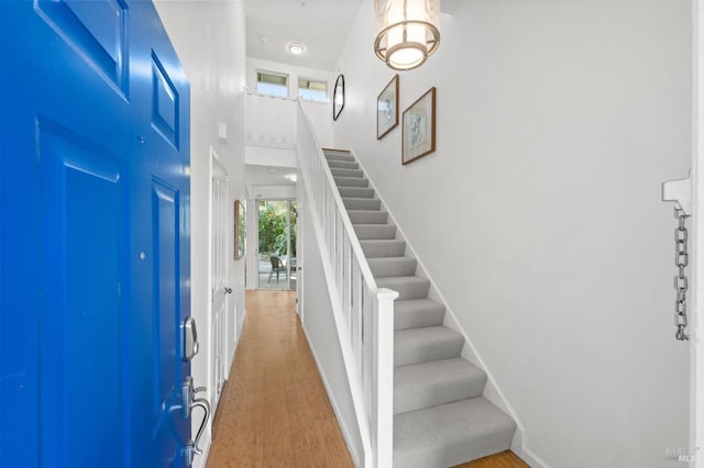 entrance foyer with wood-type flooring and a towering ceiling