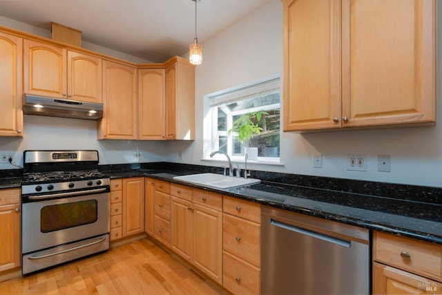 kitchen with sink, dark stone countertops, hanging light fixtures, light hardwood / wood-style floors, and stainless steel appliances