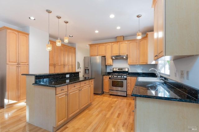 kitchen featuring dark stone countertops, a sink, appliances with stainless steel finishes, light wood-style floors, and under cabinet range hood