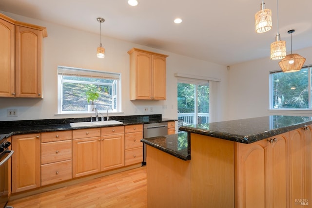 kitchen featuring sink, light hardwood / wood-style flooring, a kitchen island, pendant lighting, and dark stone counters