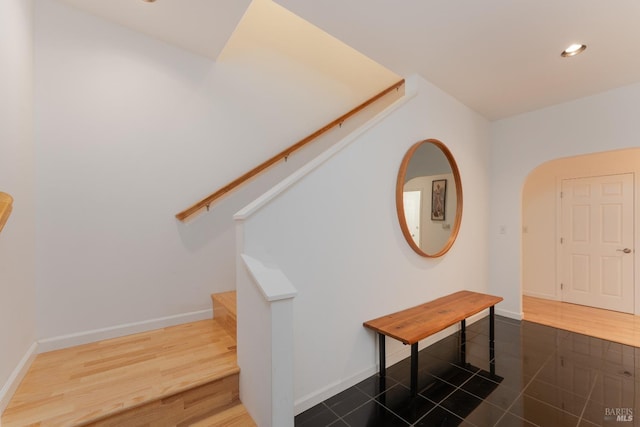 stairs with baseboards, recessed lighting, arched walkways, and wood finished floors