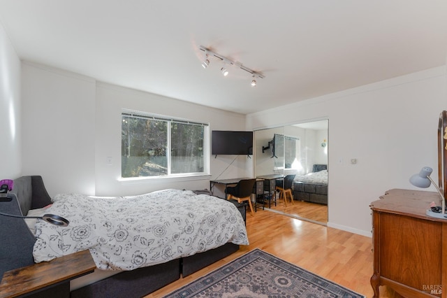bedroom with ornamental molding, rail lighting, and wood finished floors