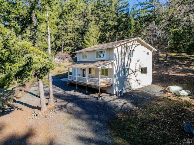 rear view of property with a porch and a view of trees
