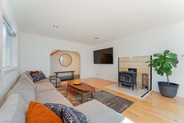 living room with wood finished floors, recessed lighting, a wood stove, and arched walkways