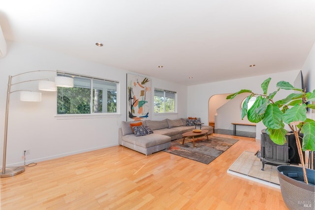 living area with a wood stove, recessed lighting, baseboards, arched walkways, and wood finished floors