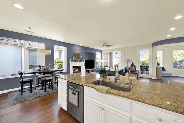 kitchen featuring dishwashing machine, sink, pendant lighting, white cabinetry, and dark stone countertops