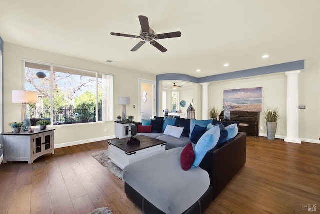 living room with dark wood-type flooring, ceiling fan, and ornate columns