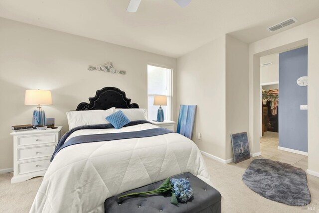 carpeted bedroom featuring a walk in closet, a closet, and ceiling fan