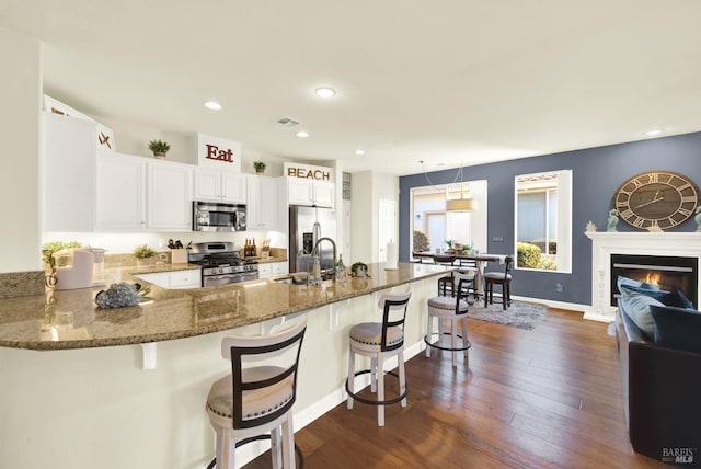 kitchen featuring dark wood-type flooring, a breakfast bar, sink, kitchen peninsula, and stainless steel appliances