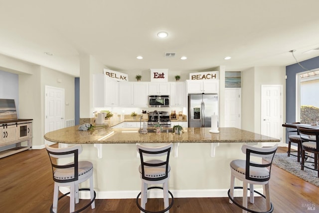 kitchen with dark wood-type flooring, a kitchen breakfast bar, kitchen peninsula, stainless steel appliances, and white cabinets