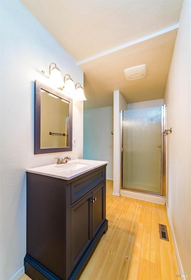 bathroom featuring hardwood / wood-style flooring, vanity, and a shower with door