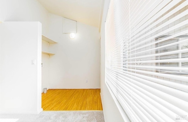 corridor with lofted ceiling and light carpet