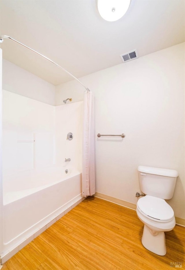 bathroom featuring hardwood / wood-style flooring, shower / tub combo, and toilet