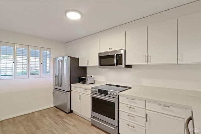 kitchen with white cabinets, appliances with stainless steel finishes, light wood-type flooring, and light countertops