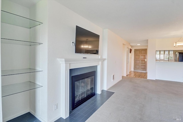 unfurnished living room featuring a fireplace with flush hearth, visible vents, and carpet