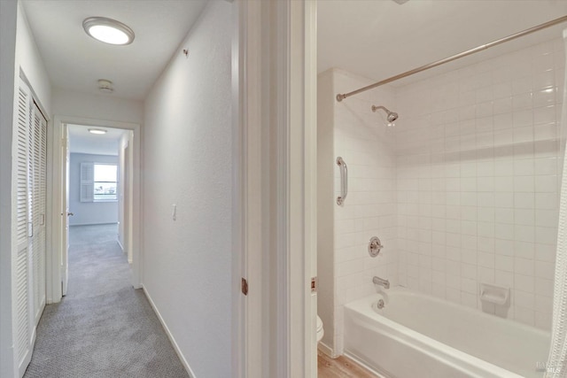 bathroom with shower / bath combination, baseboards, and toilet