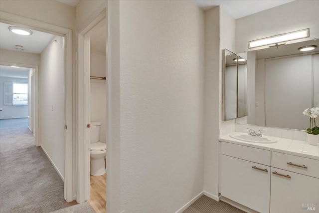 bathroom with toilet, vanity, and baseboards