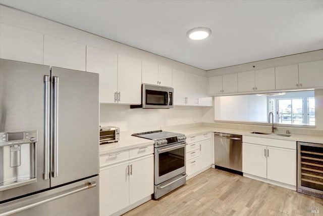 kitchen featuring a sink, wine cooler, appliances with stainless steel finishes, and white cabinetry