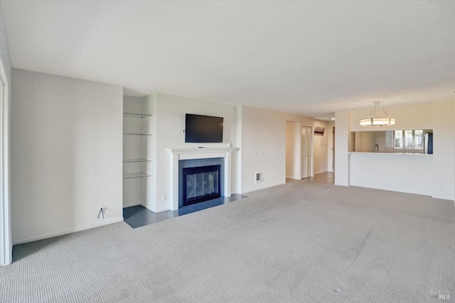 unfurnished living room with a tiled fireplace, carpet flooring, and visible vents