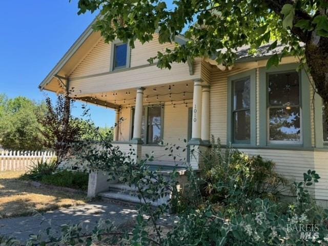 view of front of house featuring a porch and fence