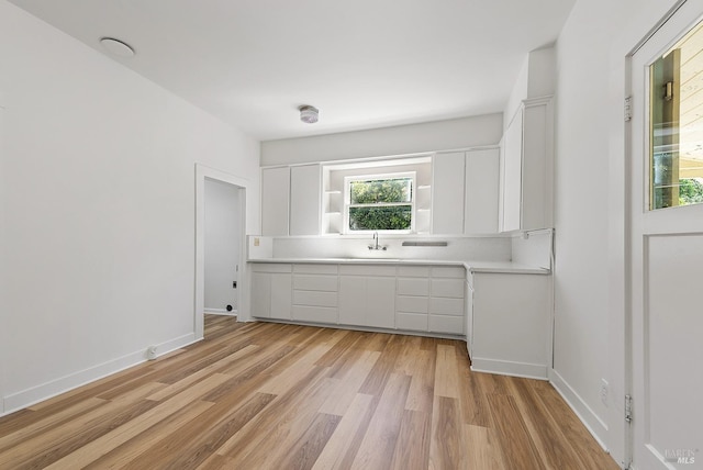 interior space with white cabinets, light countertops, light wood-style floors, and a sink