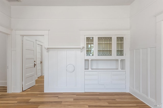 interior space featuring light wood-style floors, a decorative wall, and wainscoting