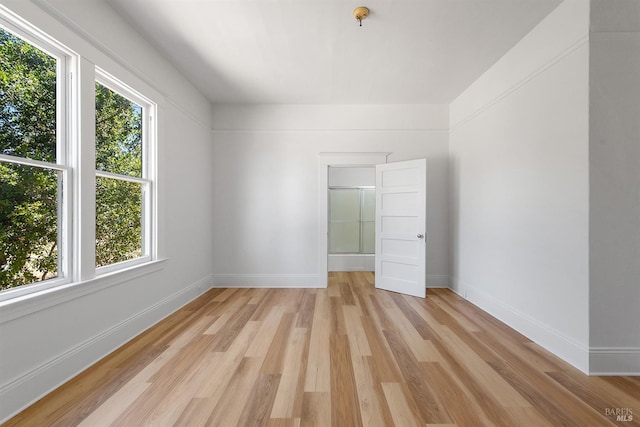 spare room with baseboards and light wood-style flooring