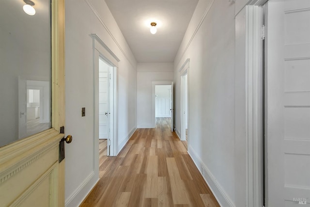 corridor featuring baseboards and light wood-type flooring