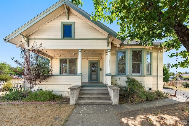 bungalow-style home featuring crawl space, fence, and a porch