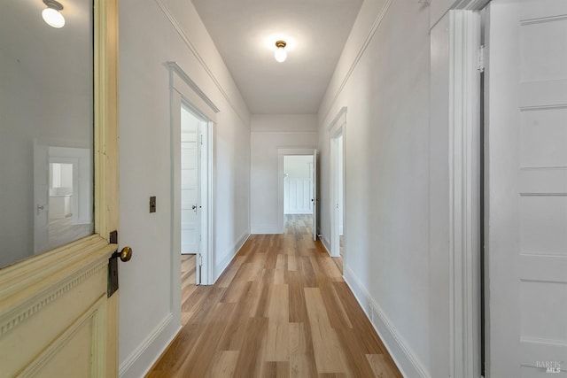 corridor featuring light wood-style floors and baseboards