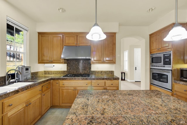 kitchen with stainless steel appliances, decorative light fixtures, and sink