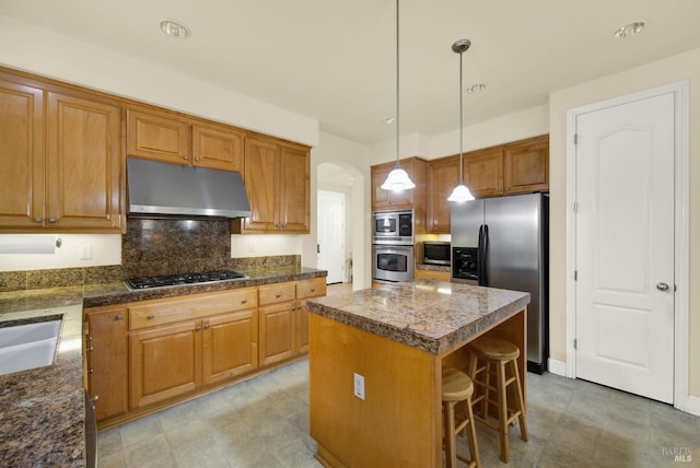 kitchen with a breakfast bar area, tasteful backsplash, a kitchen island, pendant lighting, and stainless steel appliances