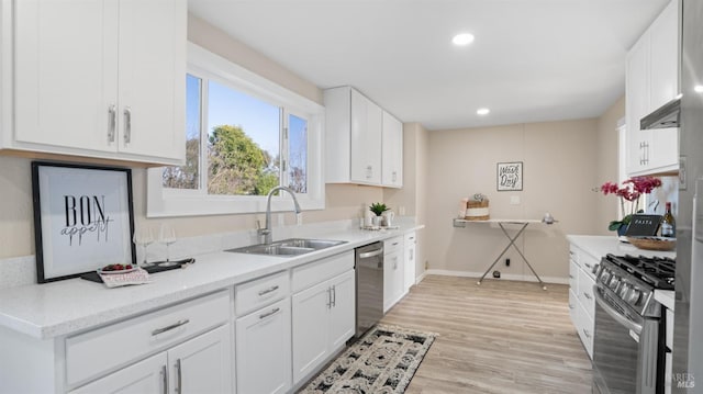 kitchen featuring appliances with stainless steel finishes, light hardwood / wood-style floors, sink, and white cabinets