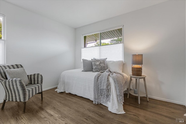 bedroom with multiple windows, wood finished floors, and baseboards