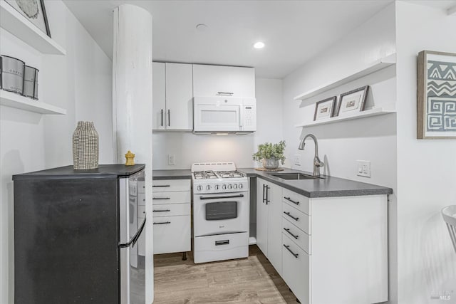 kitchen with open shelves, dark countertops, white cabinets, a sink, and white appliances