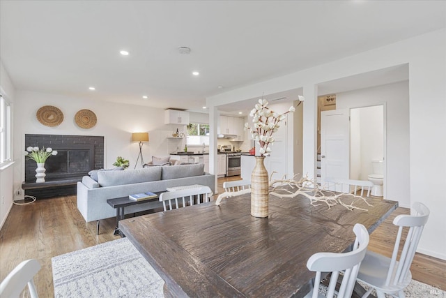 dining area featuring light wood finished floors, a fireplace, and recessed lighting