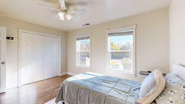 bedroom featuring hardwood / wood-style flooring, radiator heating unit, ceiling fan, and a closet