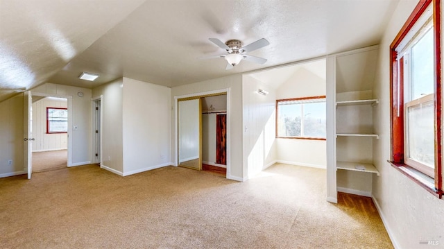 unfurnished bedroom with lofted ceiling, ceiling fan, multiple windows, light carpet, and a closet