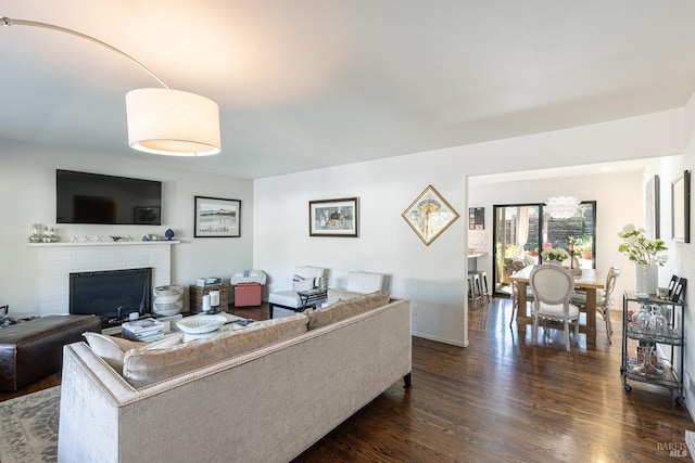 living room with a brick fireplace and dark hardwood / wood-style floors