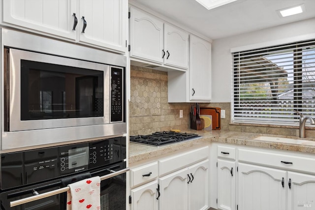 kitchen with white cabinetry, appliances with stainless steel finishes, sink, and decorative backsplash