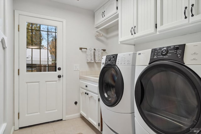 laundry room featuring light tile patterned flooring, cabinets, and washer and clothes dryer