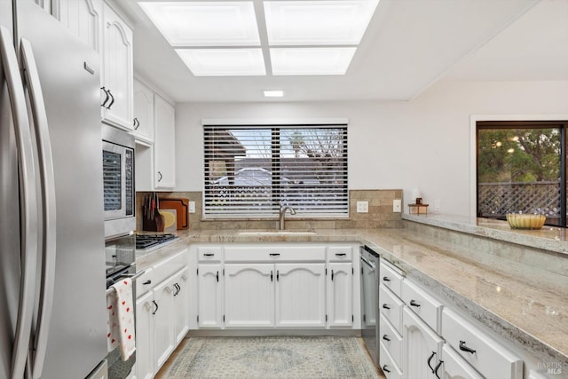 kitchen featuring plenty of natural light, appliances with stainless steel finishes, sink, and white cabinets